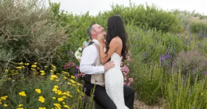 A couple hugs and kisses amongst the flowers at SpiriTaos Gardens after their wedding