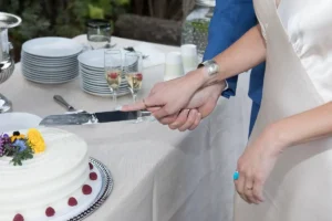 Closeup view of the groom and bride's hands cutting the cake