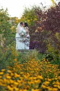 Brides posing for a photo amongst flowers at SpiriTaos Gardens