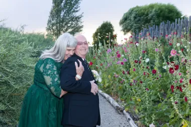An older happy couple hug in the gardens at SpiriTaos