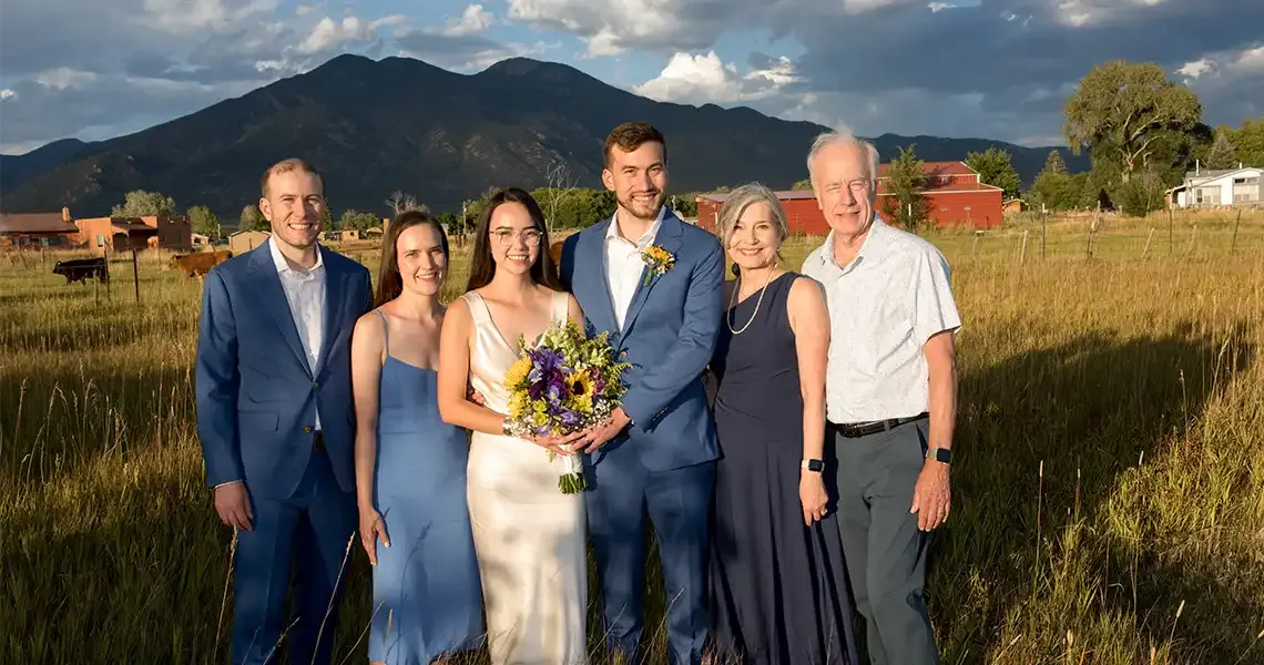 The bridal party poses for a photo with Taos Mountain in the background