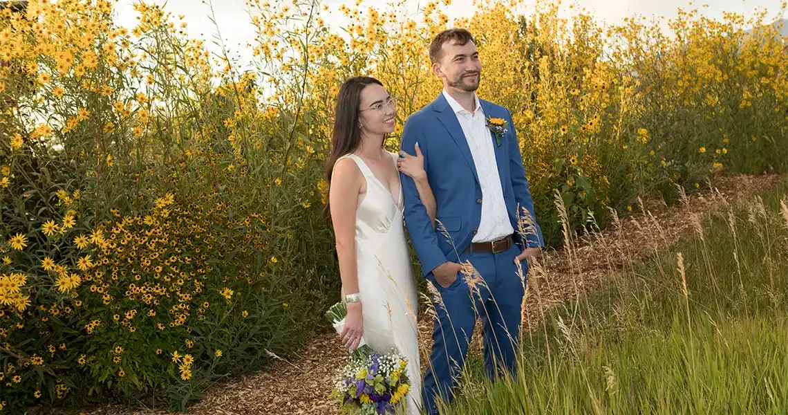 A yellow backdrop of flowers is the perfect color for this newly married couple in Taos NM