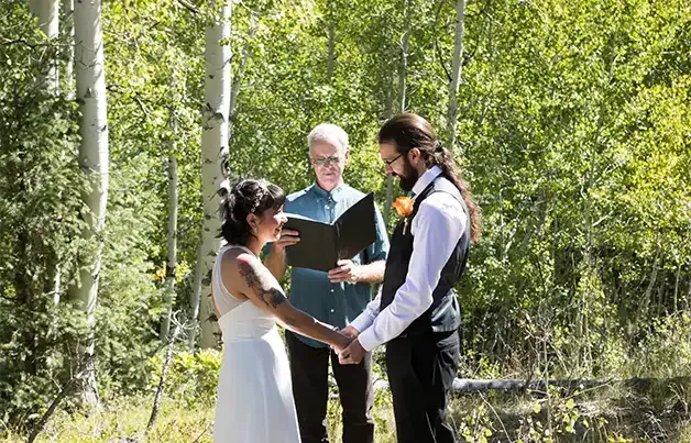 Dan Jones officiates a wedding outdoors on a sunny day in the woods