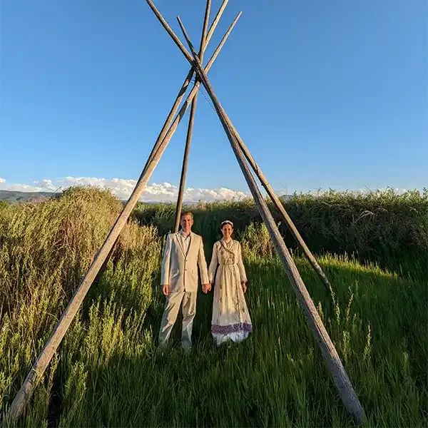 A couple poses under blue skies for their wedding portrait in Taos NM