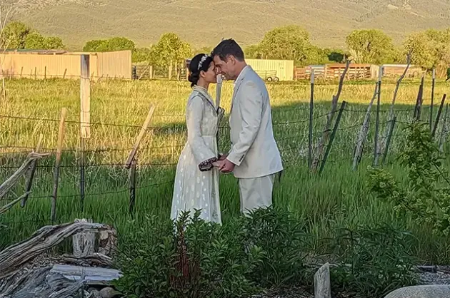 Wedding portrait of a couple touching heads with sunlit meadow behind them